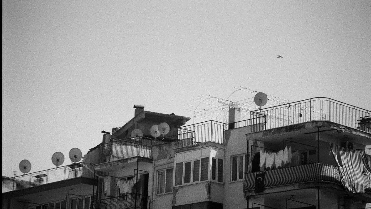 Black and white photo of urban rooftops with satellite dishes. Vintage style.