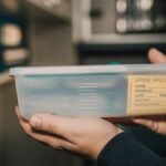 Close-up of hands holding a urine specimen container in a lab environment.