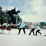 A group of schoolchildren play tug of war by the Babur statue in Navoi Square, Andijan, Uzbekistan.