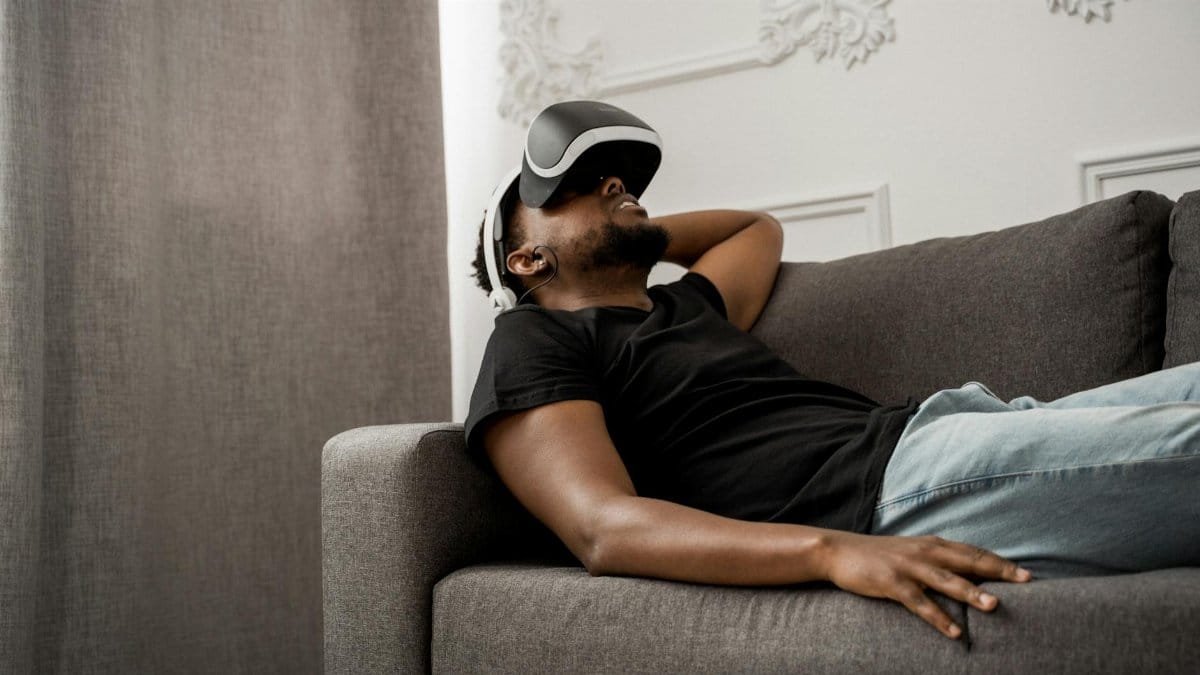 A man enjoying a virtual reality experience while reclining on a couch indoors.