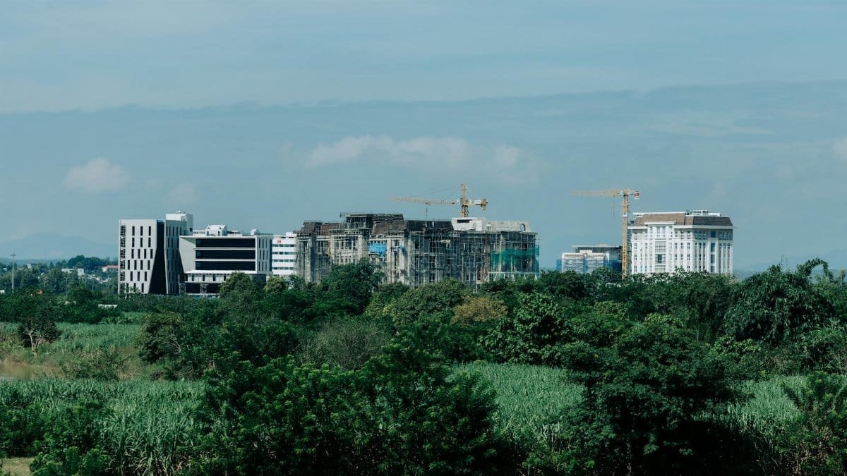 Cityscape of Kon Tum, Vietnam showing urban development amidst greenery with construction cranes.