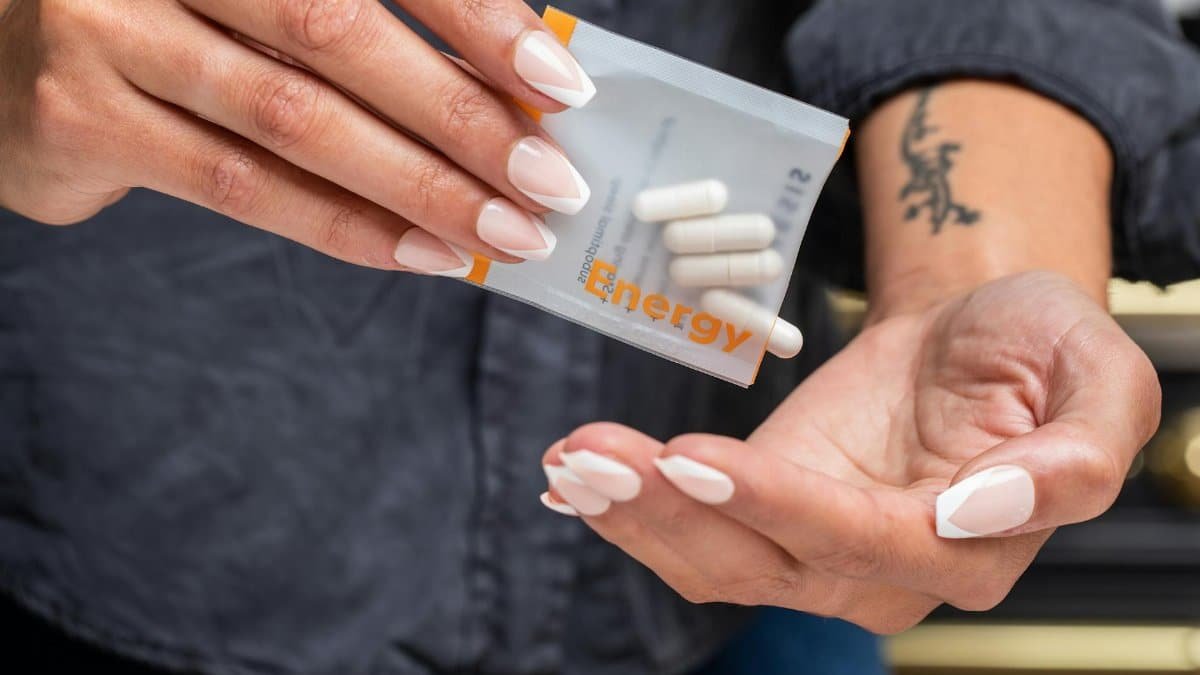 Close-up of woman's hands holding a packet of energy supplement capsules.