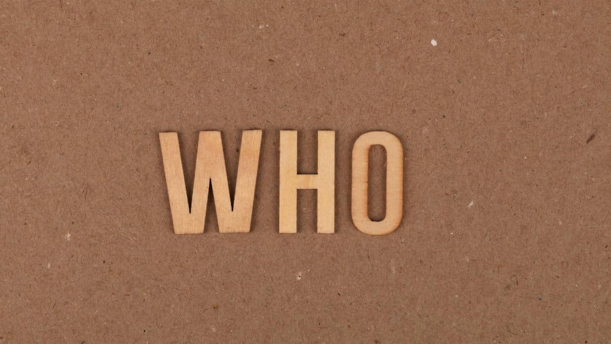 Wooden letters forming the word WHO on a textured cardboard surface.