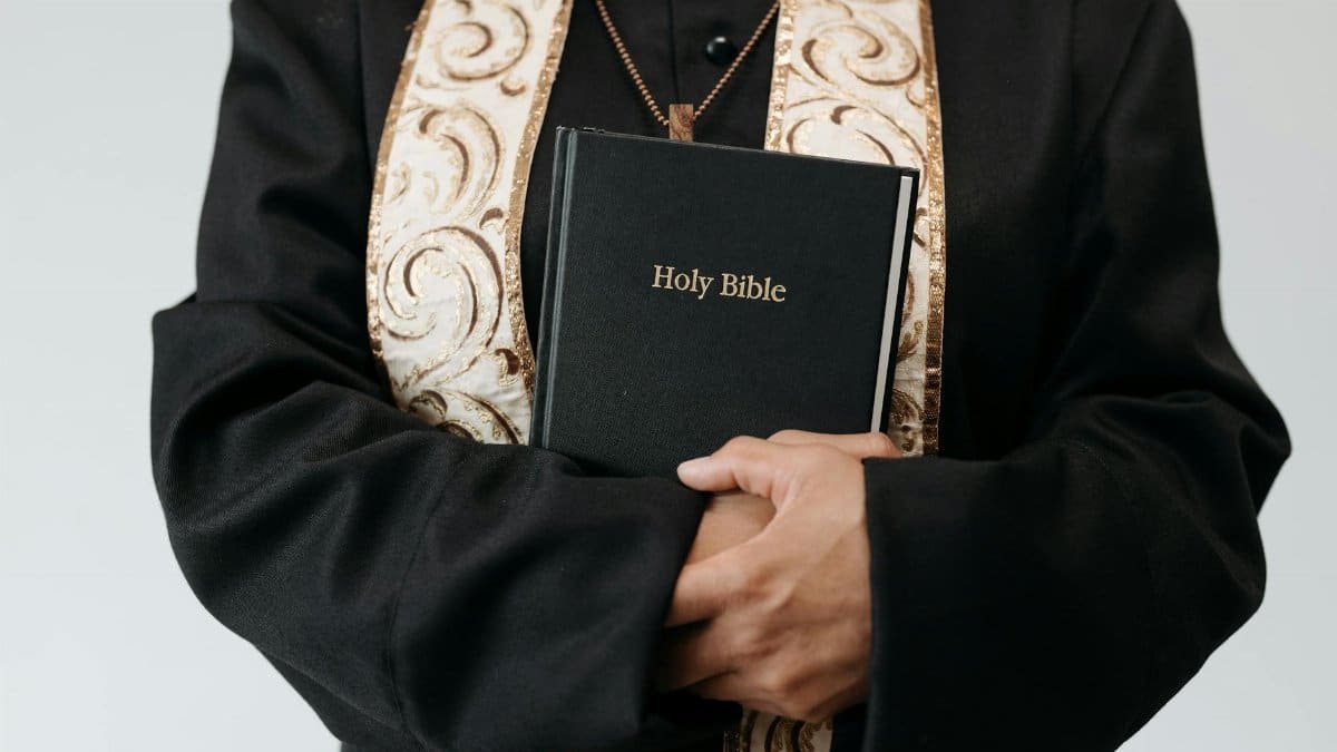 Close-up of a religious figure in vestments holding the Holy Bible, symbolizing faith and spirituality.