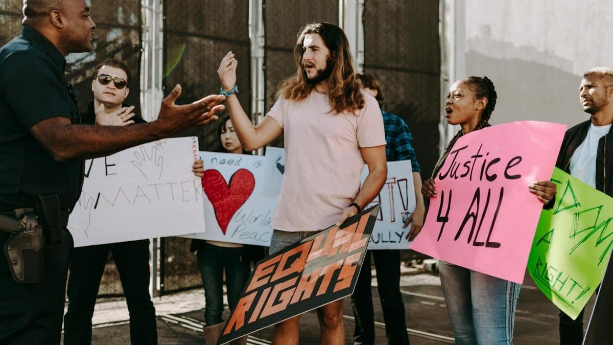 Diverse group of activists holding signs engaging with a policeman during a street protest.