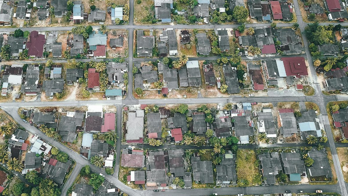 Drone view of roofs of aged residential houses near straight roads in suburb