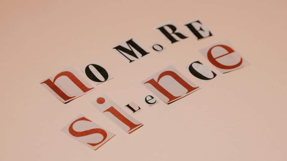 Typography artwork using cutout letters spells 'No More Silence' against a beige background.