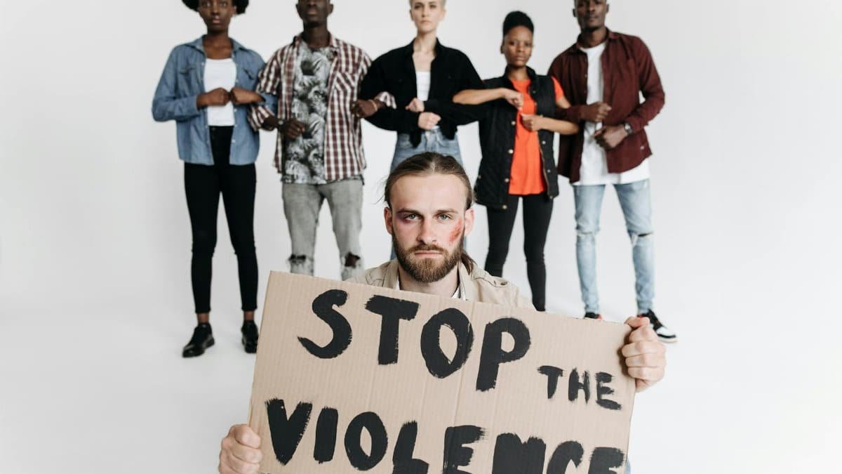 A group of people holding a cardboard sign that reads 'Stop the Violence' during a studio protest shoot.
