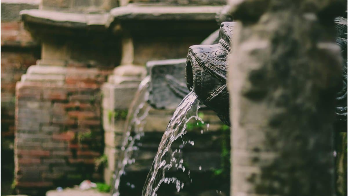 Intricately carved dhungedhara in Patan, Nepal with flowing water feature.