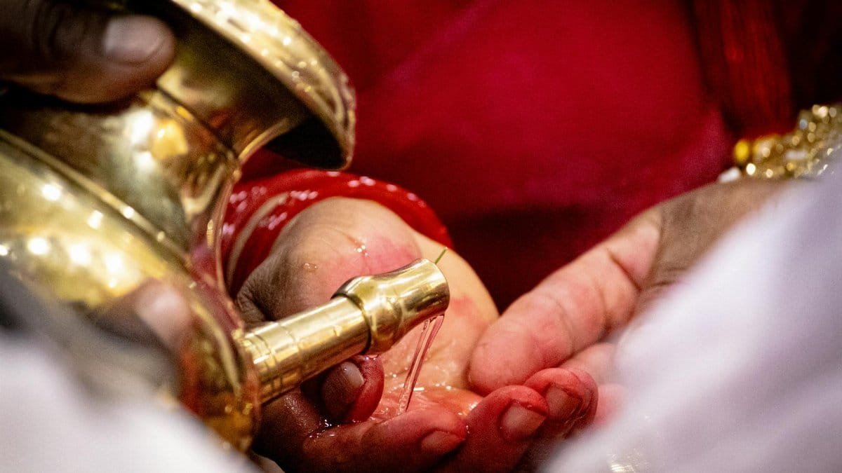 Close-up of hands performing a traditional water pouring ritual, capturing cultural and spiritual essence.