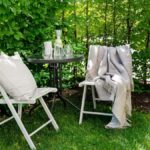 Relaxing outdoor patio setup with chairs, table, and green garden backdrop.