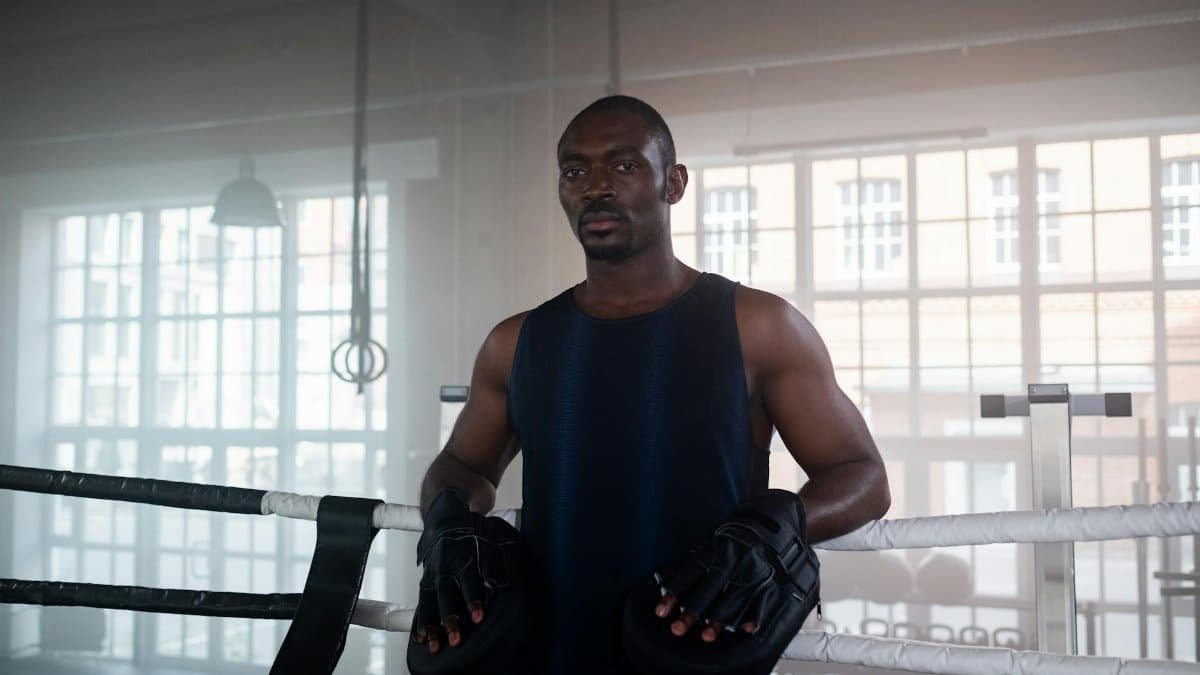 Determined boxer standing in a boxing ring, ready for training indoors.