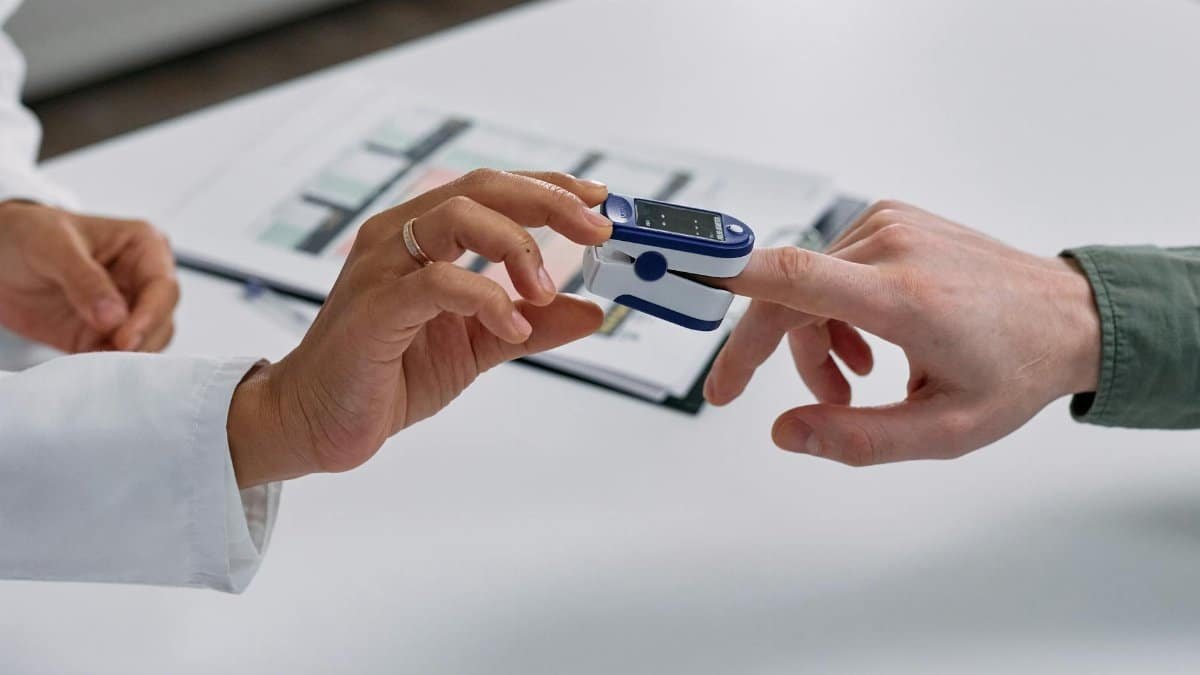 Close-up of a fingertip pulse oximeter being used to measure a patient's heart rate and oxygen levels.