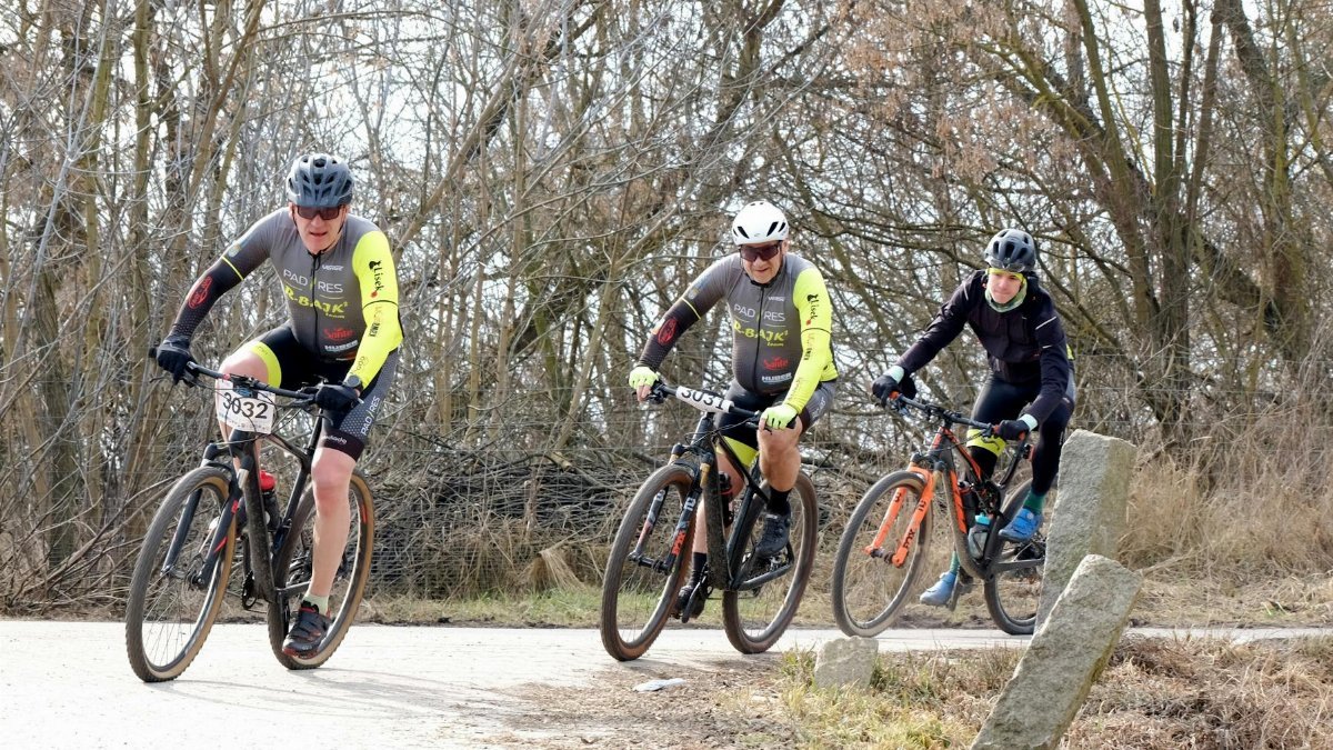 Three cyclists participating in a forest trail race during autumn, showcasing teamwork and endurance.