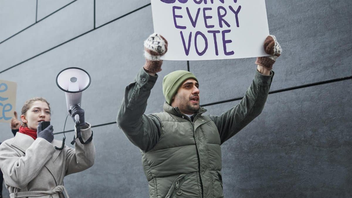 Protesters holding signs and a megaphone, demanding every vote to be counted during a winter rally.