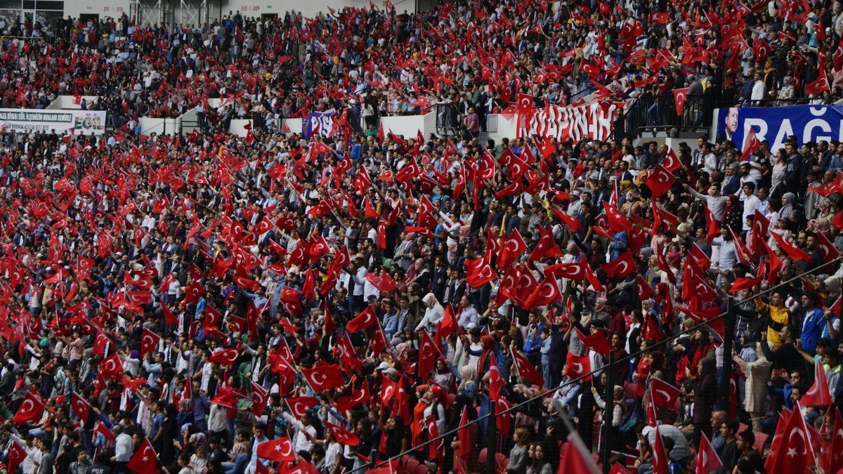 Lively crowd waving Turkish flags in a stadium setting, showing national pride.