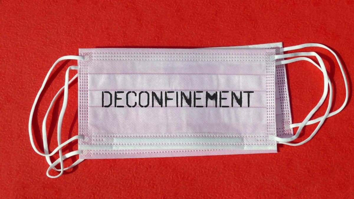 Image of a surgical mask with 'Deconfinement' text on a vibrant red surface.