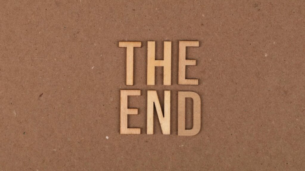 Wooden letters spelling 'The End' on a cardboard background.