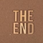 Wooden letters spelling 'The End' on a cardboard background.