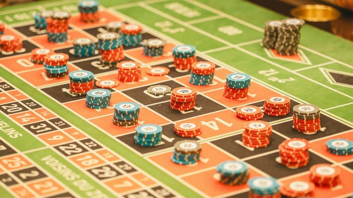 Colorful roulette table with stacks of casino chips in a lively atmosphere.