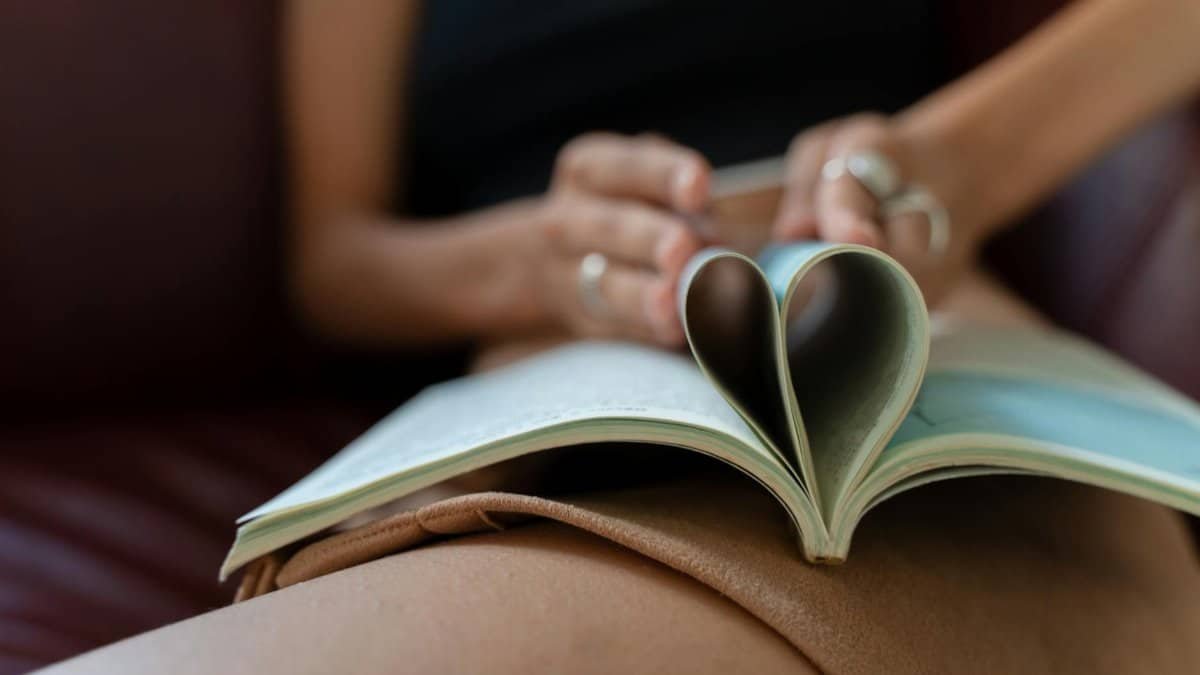 Close-up of a person's hands holding a book with pages folded into a heart shape.