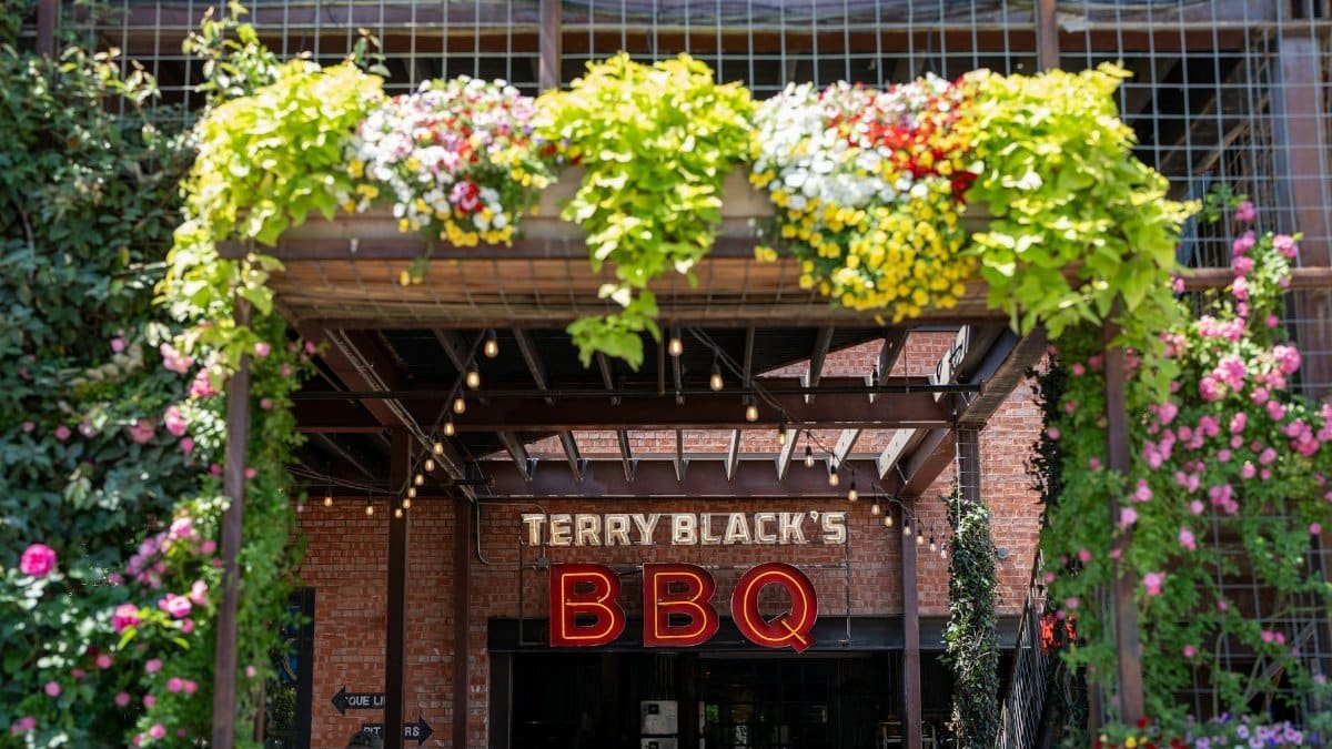 Entrance of Terry Black's BBQ with vibrant flowers in Dallas, Texas.