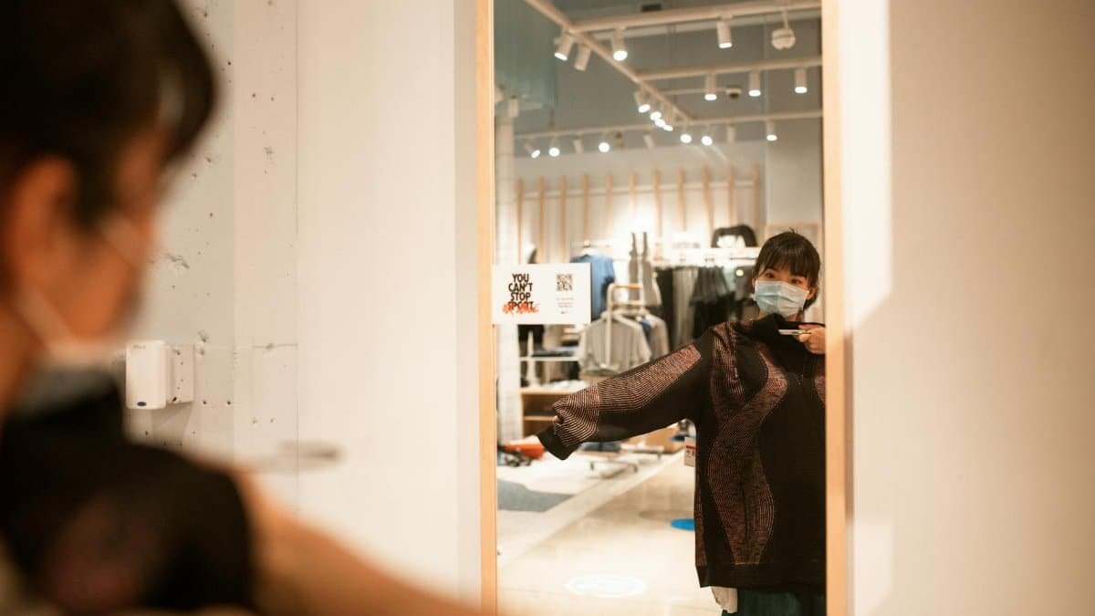 Woman wearing a face mask trying on clothes in a store during pandemic.