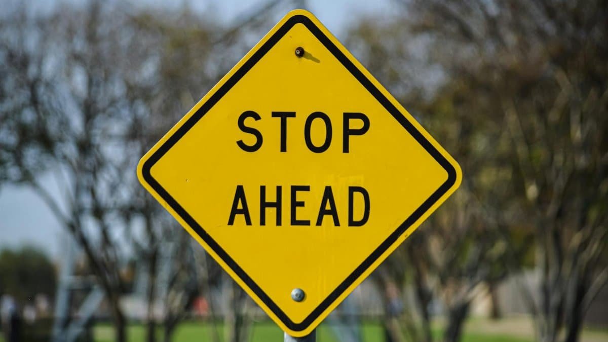 Vibrant yellow stop ahead sign in an outdoor park setting in Dallas, Texas.
