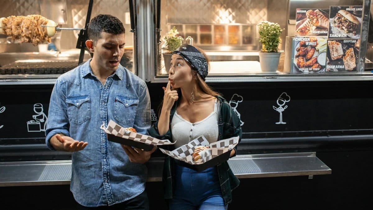 A couple enjoys street food from a food truck at night, sharing fun moments.