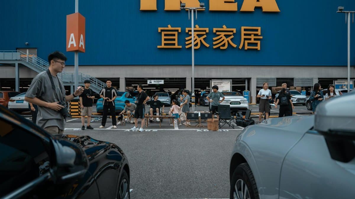 People enjoying a social gathering at an IKEA parking lot with cars and a large store sign.
