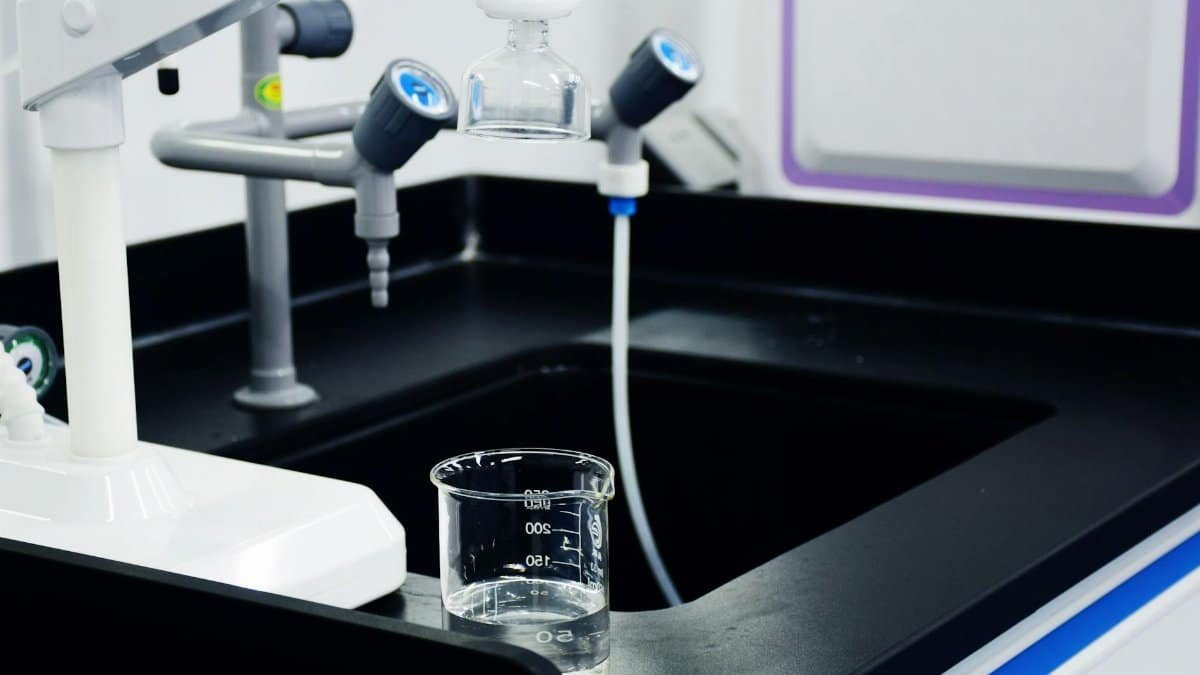 Close-up of laboratory equipment used for water filtration, featuring beakers and faucets.