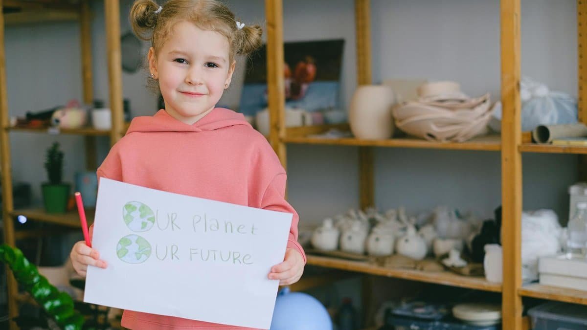 Young girl holding a poster promoting environmental awareness and the future of our planet.