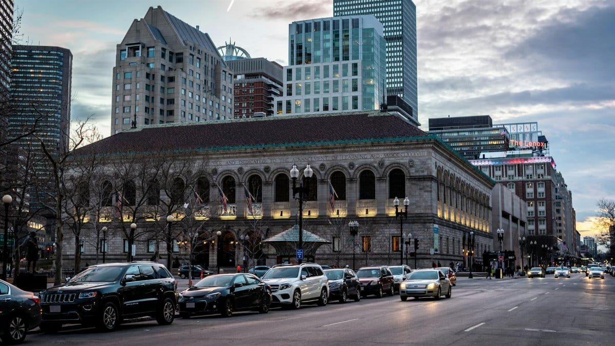 A street view of Boston Public Library and skyline at dusk, capturing urban architecture and city life.