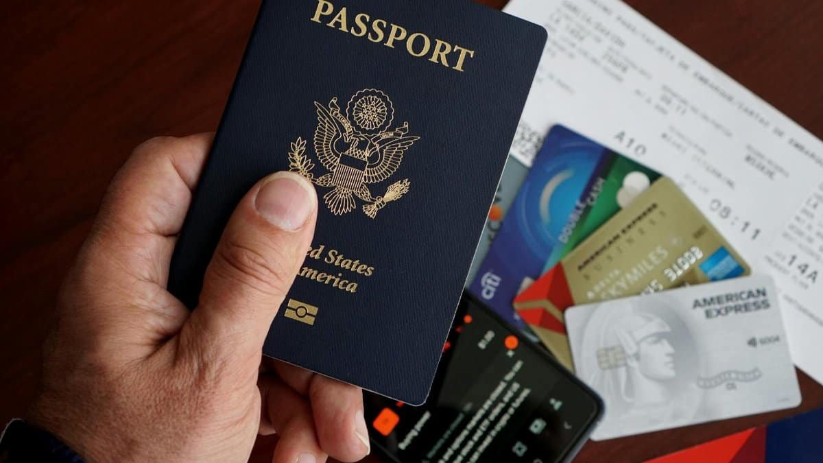 A close-up of a US passport with credit cards, tickets, and a mobile phone on a table.