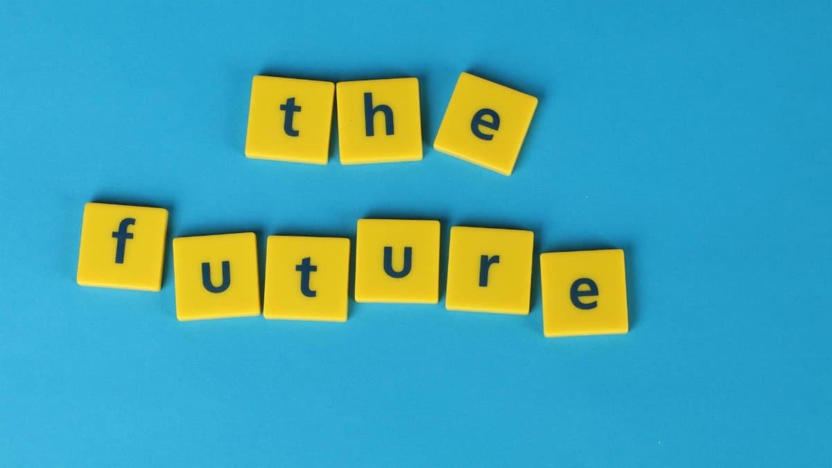 Yellow letter tiles spelling 'the future' on a blue surface, minimalist style.