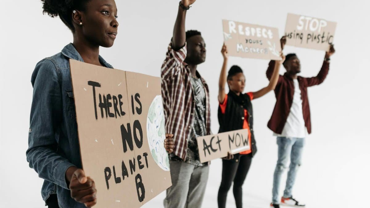 Diverse group holding protest signs advocating for climate action with phrases like 'There is No Planet B'.