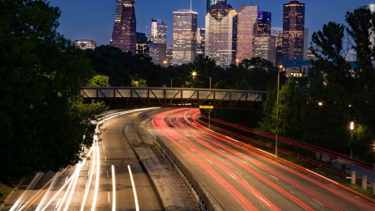 Long exposure shot of Houston's skyline at night with vibrant light trails leading into the city.