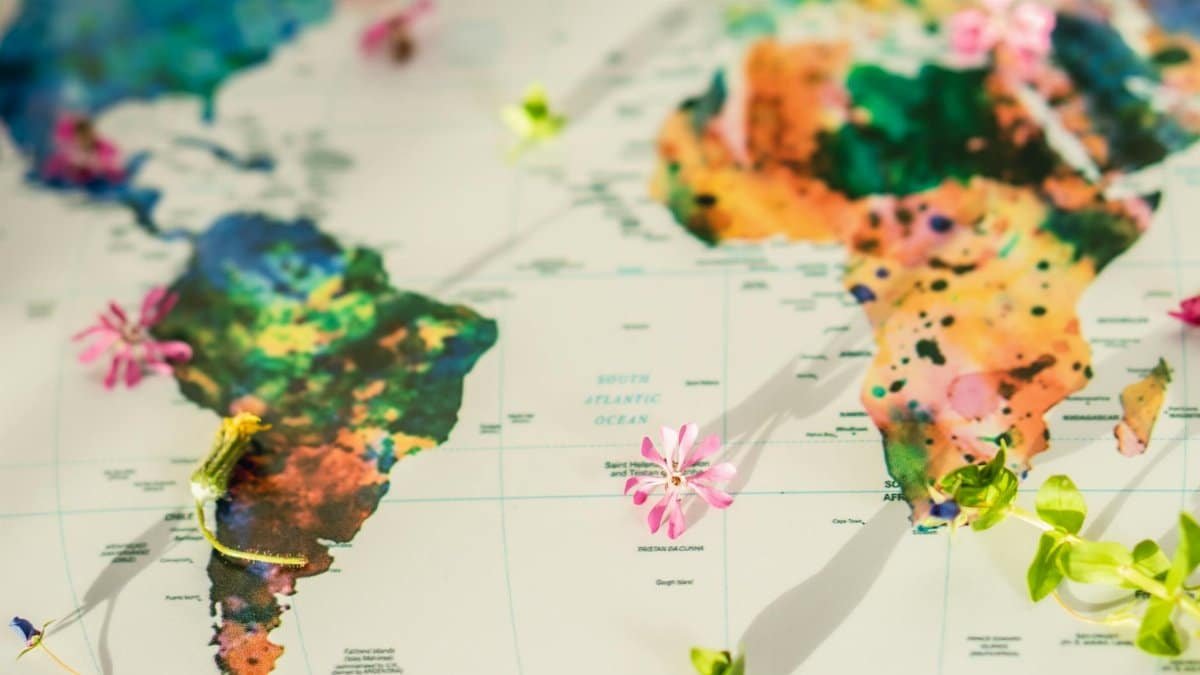 Colorful world map adorned with flowers and green leaves symbolizing global peace and nature.
