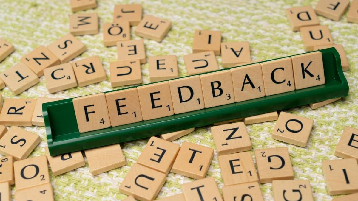 Wooden letter tiles spelling 'feedback' on a green rack, representing communication and evaluation.