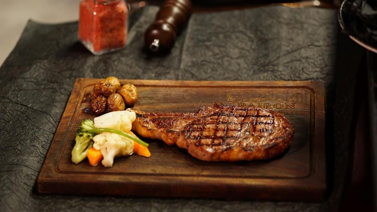 Delicious grilled steak paired with roasted potatoes and vegetables on a wooden board.