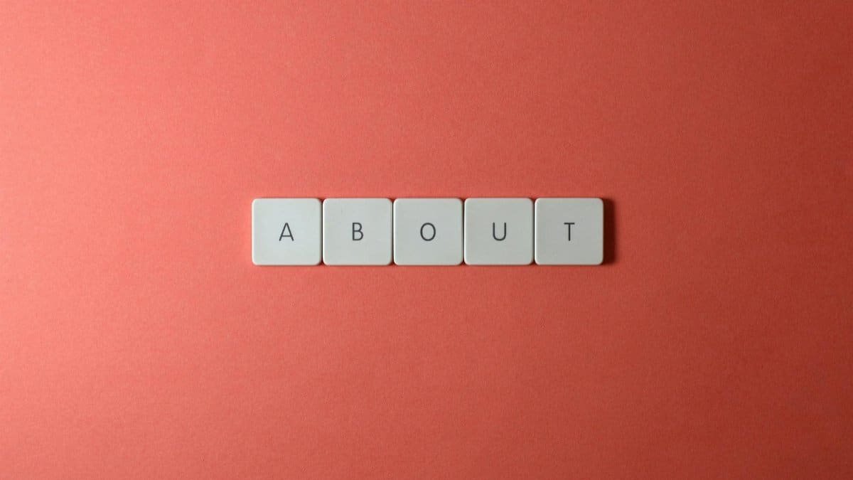 Close-up of keyboard buttons spelling 'ABOUT' against a red surface, minimalist style.