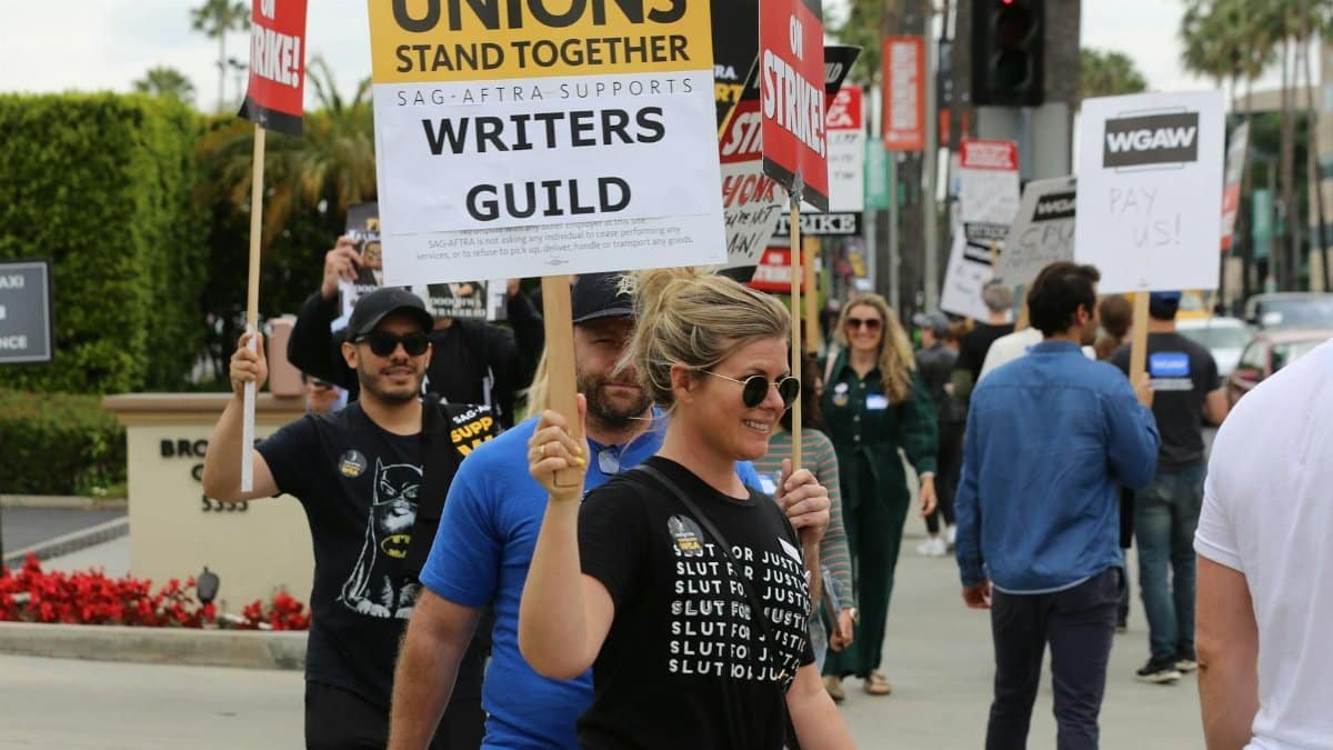 Group of protesters with placards supporting Writers Guild on a street demonstration.