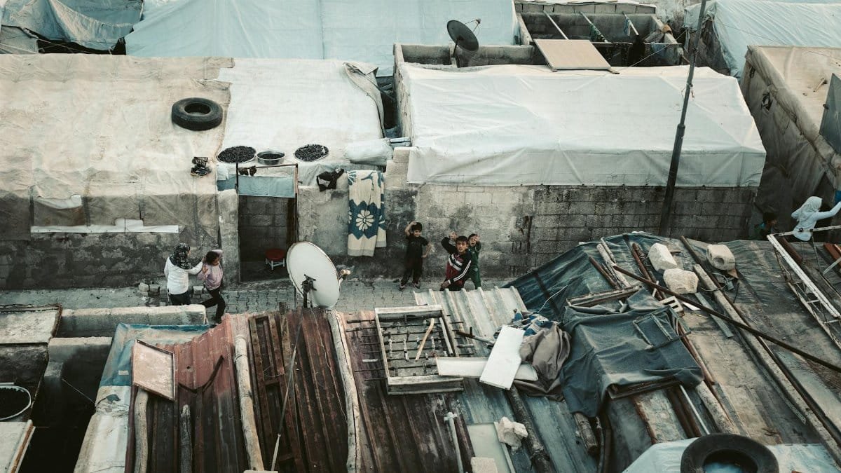 Aerial image showing rooftops and people in a Syrian refugee camp.