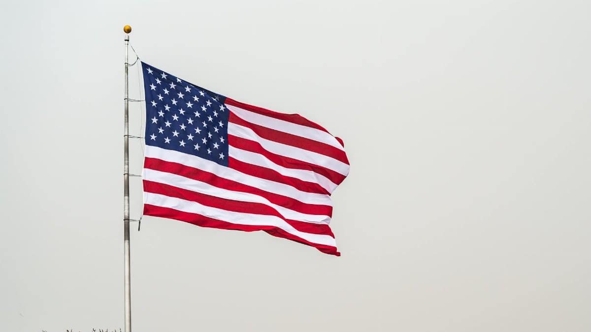 A striking image of the American flag waving on a flagpole set against a clear sky.
