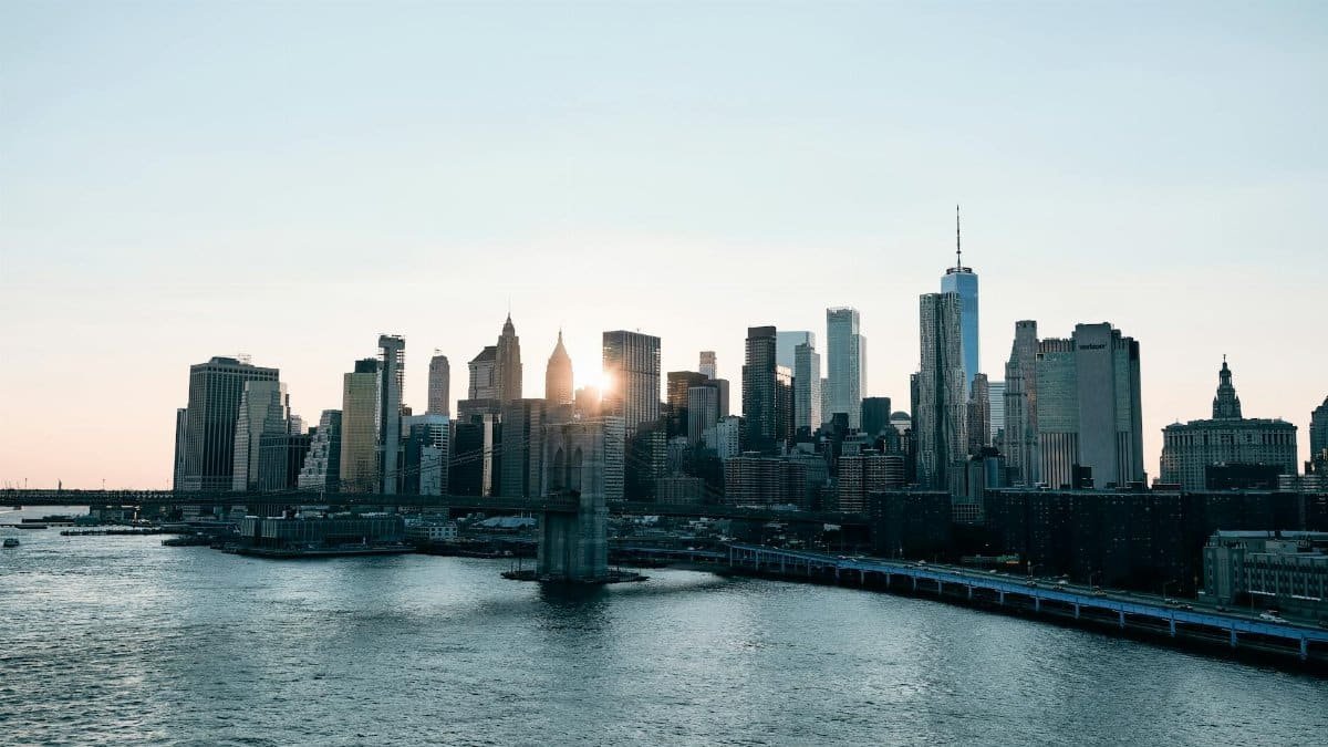 Stunning view of New York City's skyline with skyscrapers and river at sunrise.