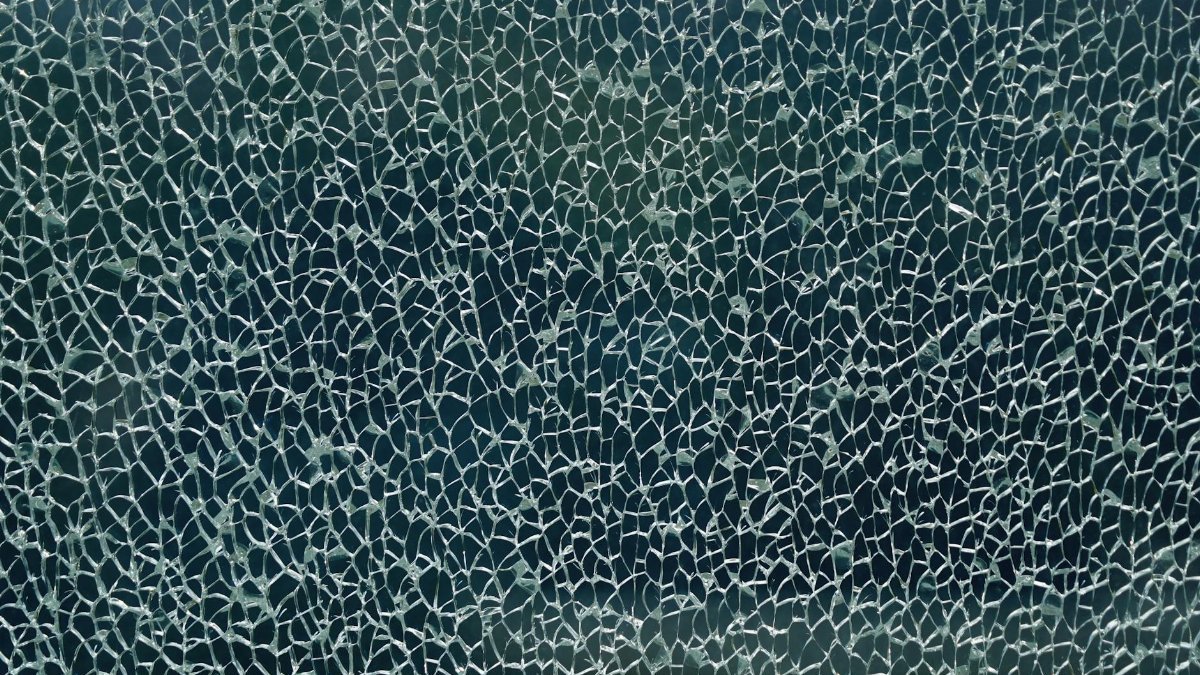 Close-up of shattered glass forming an intricate web-like pattern, showcasing unique texture and abstract forms.