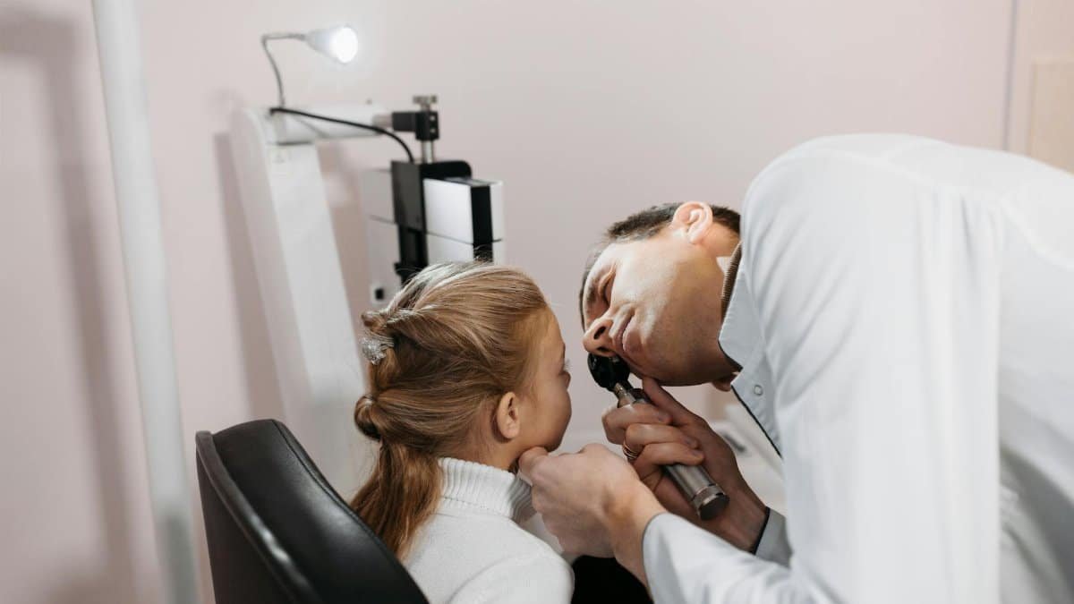 A doctor examines a young girl's ear during a medical appointment in a clinic.