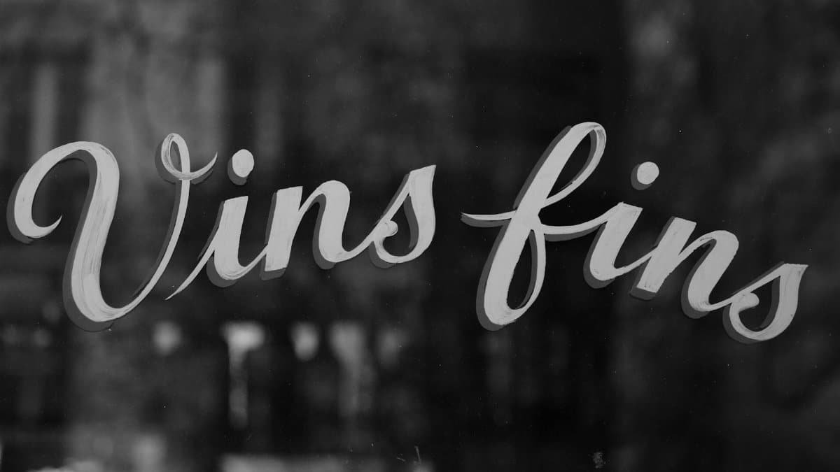 Black and white image of a cafe window in Paris with 'Vins fins' text, symbolizing fine wines.
