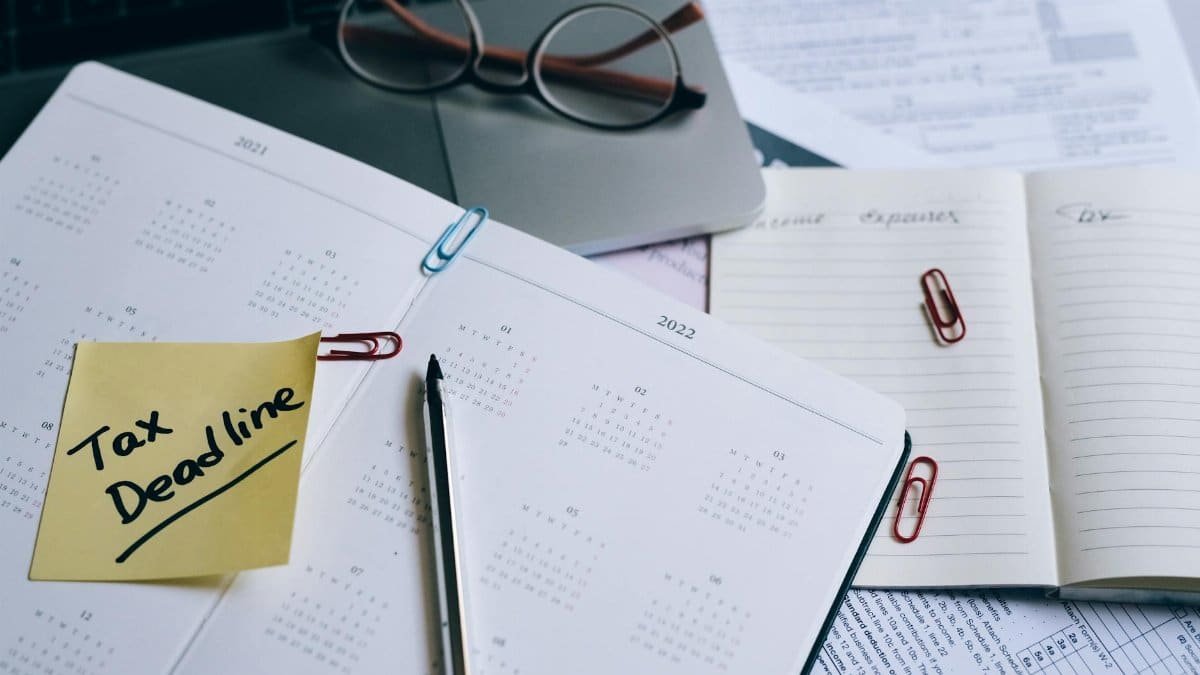A desk with a planner, sticky note marked 'Tax Deadline', and paperwork, indicating financial planning.