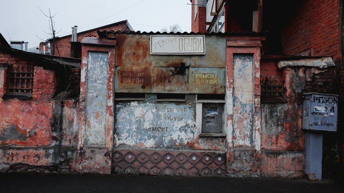 A deteriorating wall with rustic textures and faded signage showcasing urban decay in a vibrant city setting.